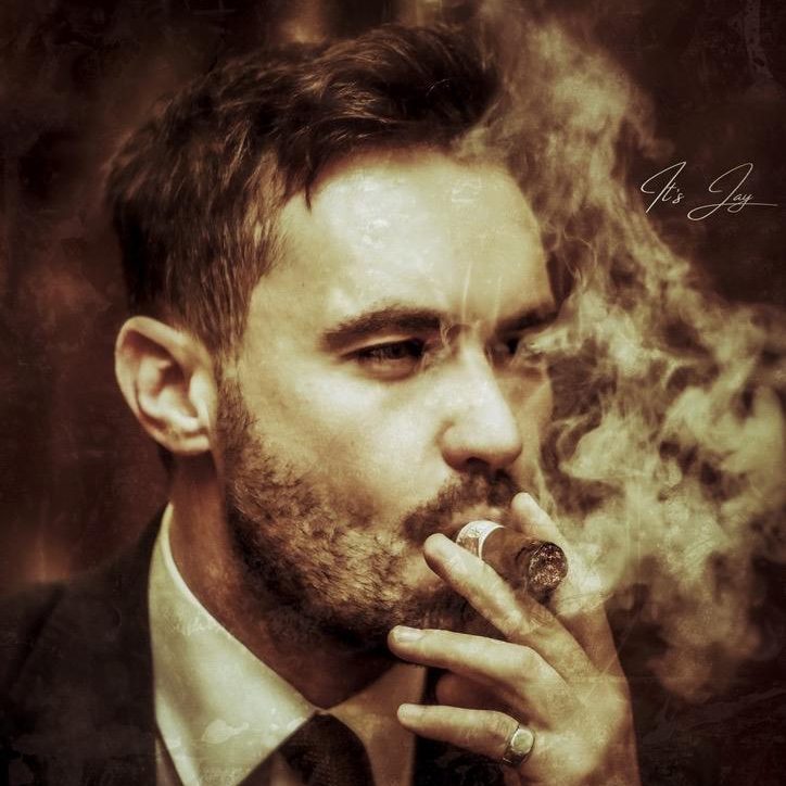 Moody portrait of a gentleman smoking a cigar, exuding sophistication and timeless charm.